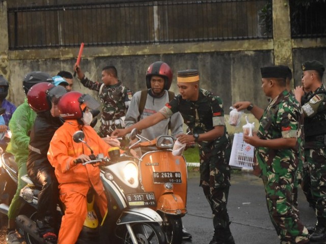 Dibawah guyuran hujan, Prajurit Yonif Mekanis 201/JY tetap berbagi takjil kepada masyarakat