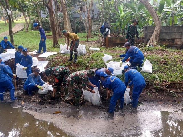 Kolaborasi Babinsa Kelurahan Lubang Buaya Bersama Petugas Dinas Tata Air Bersihkan Saluran Air